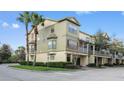 View of a three-story stucco townhome with mature landscaping and a two-car garage at 2604 Grand Central Pkwy # 12, Orlando, FL 32839