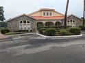 Charming community clubhouse with stone accents, a red tile roof, and inviting landscaping at 2836 Club Cortile Cir, Kissimmee, FL 34746