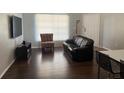 Comfortable living room with dark wood floors, black sofa, TV, and patterned chair at 3651 N Goldenrod Rd # 210, Winter Park, FL 32792
