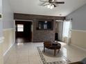 Bright living room with tile flooring, ceiling fan, and a decorative stone accent wall with mounted television at 5323 Alcom Dr, Orlando, FL 32812