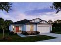 New construction of a one-story home with red entry door, white stucco, stone accents and an attached two-car garage at 6634 Lullaby Way, Mascotte, FL 34753