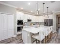 Bright kitchen featuring white cabinets, stainless steel appliances, quartz countertops, and a large island with bar stools at 6634 Rhythm Dr, Mascotte, FL 34753