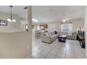 Open living room features tile floors, a ceiling fan, and access to the kitchen area at 1739 Nectarine Trl, Clermont, FL 34714