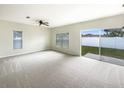 Spacious living room featuring neutral carpet, a ceiling fan, and a sliding glass door to the backyard at 240 Whispering Pines Way, Davenport, FL 33837