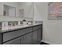 Stylish bathroom featuring double sinks with granite counters, gray cabinets, and modern fixtures at 2813 Jamaica Way, Haines City, FL 33844