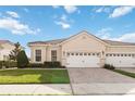 Charming single-story home featuring a tile roof, brick driveway, and well-manicured lawn at 2865 Eastham Ln, Kissimmee, FL 34741