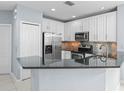 Modern kitchen featuring stainless steel appliances, white cabinets, dark countertops, and a breakfast bar at 3575 Victoria Pines Dr # 276, Orlando, FL 32829