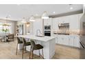 Stylish kitchen island with seating, white cabinets, stainless steel appliances, and modern pendant lighting at 6257 Dew Drop Loop, St Cloud, FL 34771