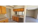 Kitchen featuring stainless steel sink, matching dishwasher and wood cabinets, and an open view to the dining area at 12151 Goldenstar Ln, Clermont, FL 34711