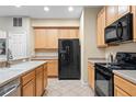 Bright kitchen featuring tile floors, wooden cabinetry, stainless steel sink and black appliances at 1270 Falling Star Ln, Orlando, FL 32828
