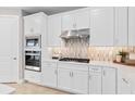 Stylish kitchen with white cabinets, stainless steel appliances, a gas range, and decorative tile backsplash at 1941 Spring Shower Cir, Kissimmee, FL 34744