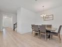 Open-concept dining room featuring wood floors, a modern chandelier, and access to the staircase at 4484 Lions Gate Ave, Clermont, FL 34711