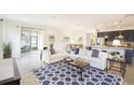 Open-concept living room showcasing a tile floor, white sofas, a blue patterned rug, and a kitchen view at 6552 Rhythm Dr, Mascotte, FL 34753
