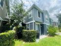 Exterior view of a two-story home featuring gray siding, neatly trimmed hedges and a tree for shaded privacy at 6640 S Goldenrod Rd # 118B, Orlando, FL 32822