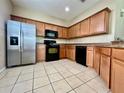 Well-lit kitchen featuring wood cabinets, stainless steel refrigerator, and black appliances at 6640 S Goldenrod Rd # 118B, Orlando, FL 32822
