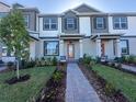 Beautifully designed townhome with gray and white exterior, lush landscaping, and a welcoming walkway to the front door at 9338 Bolshoi Aly, Winter Garden, FL 34787