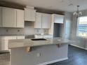 Bright kitchen with white cabinets, gray countertops, subway tile backsplash, and a kitchen island at 9338 Bolshoi Aly, Winter Garden, FL 34787