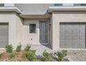 Well-maintained townhome with a gray front door, single-car garage, and lush greenery at 1209 S Station Pl # 306, Orlando, FL 32809