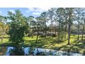 Spacious lot with mature trees and view of the brick home from across the lake, reflecting in the clear water at 5203 Pineview Way, Apopka, FL 32703