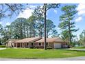 Brick house with an attached garage, covered front porch with rocking chairs and expansive front lawn with mature trees at 5203 Pineview Way, Apopka, FL 32703