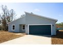 View of the house with a blue garage door, and a neatly kept lawn, reflecting modern curb appeal at 656 Marrion Oaks Mnr, Ocala, FL 34473