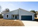 Charming single-story home featuring a blue garage door, modern design, and well-maintained front yard at 656 Marion Oaks Mnr, Ocala, FL 34473