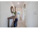 Inviting hallway with decorative console table, round mirror, and neutral tile flooring at 7077 Painted Bunting Way, St Cloud, FL 34773