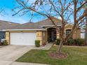 Charming single-story home featuring a two-car garage, well-maintained lawn, and mature tree at 130 Bloomingdale Dr, Davenport, FL 33897