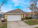 Charming single-story home featuring a two-car garage, well-maintained lawn, and manicured landscaping at 130 Bloomingdale Dr, Davenport, FL 33897