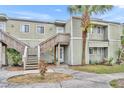 Townhouse exterior with light green siding, wood stairs, and a green lawn with a palm tree at 185 Scottsdale Sq # 185, Winter Park, FL 32792