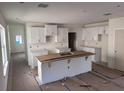 Unfinished kitchen with island, white cabinets, and stainless steel sink at 3171 Cup Dr, Lakeland, FL 33803