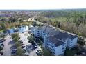 Aerial view of a multi-story apartment building nestled among lush greenery and overlooking a tranquil pond at 3176 Feltrim Pl # 205, Kissimmee, FL 34747