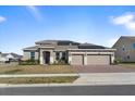 Charming home with three-car garage and a welcoming front entrance, enhanced by professional landscaping at 4897 Gilded Jewel Dr, Mount Dora, FL 32757