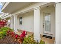 Inviting front porch featuring classic white columns, a stylish door, and colorful landscaping for curb appeal at 1432 Titian Ct, Reunion, FL 34747