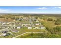 Expansive aerial view of a residential community surrounded by open fields and distant trees at 16413 Bloom Ct, Groveland, FL 34736