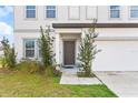 Close up of a home's entrance showcasing the front door, landscaping, and attached garage at 16413 Bloom Ct, Groveland, FL 34736
