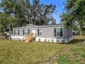 Charming gray home with black shutters and well-maintained landscaping at 5045 Se 148Th St, Summerfield, FL 34491