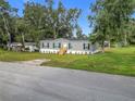Gray home with black shutters, a white door, and well-maintained landscaping at 5045 Se 148Th St, Summerfield, FL 34491