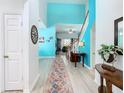 Bright foyer with high ceilings, colorful walls, wood-look flooring, and a staircase leading to the upper level at 7709 Comrow St, Kissimmee, FL 34747