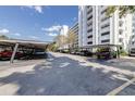 Parking lot featuring covered parking spaces on a sunny day with view of the condominium building at 1100 S Orlando Ave # 301, Maitland, FL 32751