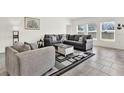 Spacious living room featuring modern gray sofas and a decorative rug on tile flooring at 425 Singing Sands Cir, Lake Wales, FL 33859