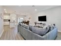 Open-concept living area with hardwood floors, a plush sofa, and modern entertainment center at 702 Pelican Ct, Kissimmee, FL 34759