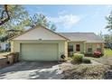 View of house with attached garage, grill, walkway and garden with a beautiful blue sky backdrop at 10320 Bumblebee Ln, Leesburg, FL 34788
