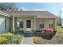 Inviting front door, featuring a lovely garden with a charming wheelbarrow filled with vibrant flowers and a paved walkway at 10320 Bumblebee Ln, Leesburg, FL 34788