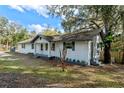 Charming exterior view of a freshly painted white brick home with gray accents and mature trees in the front yard at 1343 Spring Lake Rd, Fruitland Park, FL 34731