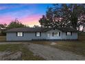 Exterior view of home with repainted facade, landscaping and mature trees during twilight at 1343 Spring Lake Rd, Fruitland Park, FL 34731