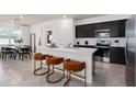 Modern kitchen featuring a center island with seating, stainless steel appliances, and dark cabinets at 1839 Groveline Rd, St Cloud, FL 34771