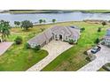 Aerial view of home with large driveway, three-car garage, water view, and green lawn at 534 Two Lakes Ln, Eustis, FL 32726