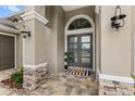 Close up of front door with stone accents, a decorative welcome mat, and stylish lighting fixtures at 534 Two Lakes Ln, Eustis, FL 32726