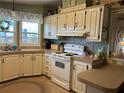 Well-lit kitchen featuring tan countertops, wooden cabinets, and a white stove at 103 Dreama Dr, Davenport, FL 33897